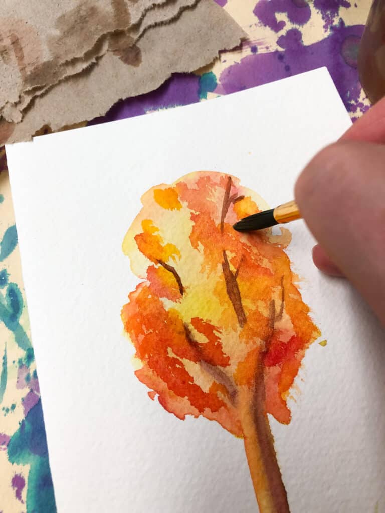 dabbing darker reds and orange watercolor paint on fall tree