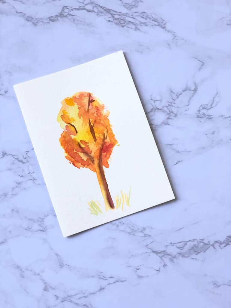 watercolor fall tree painting on marble countertop.