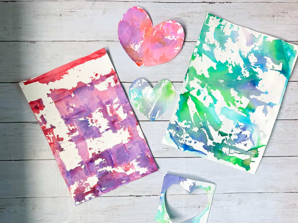 papers created with bleeding tissue paper and heart craft cut out on shiplap.