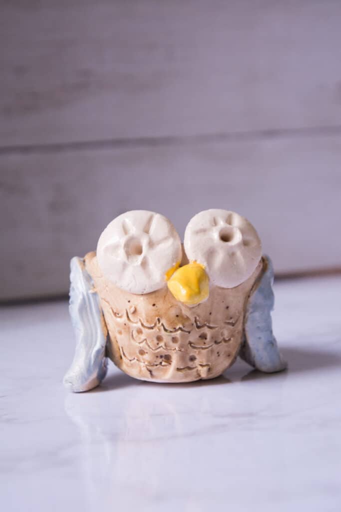 clay pinch pot owl art project for kids glazed on marble table.