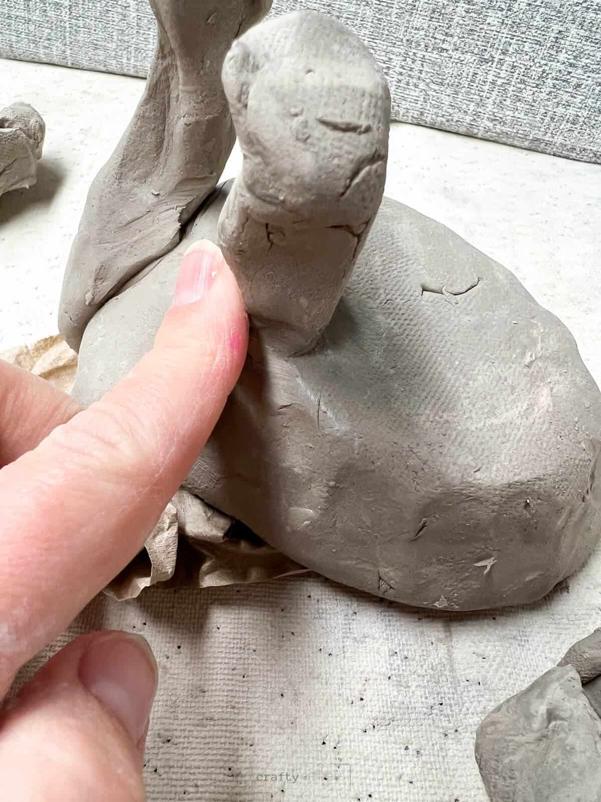 finger blending clay elephant leg on elephant art project.