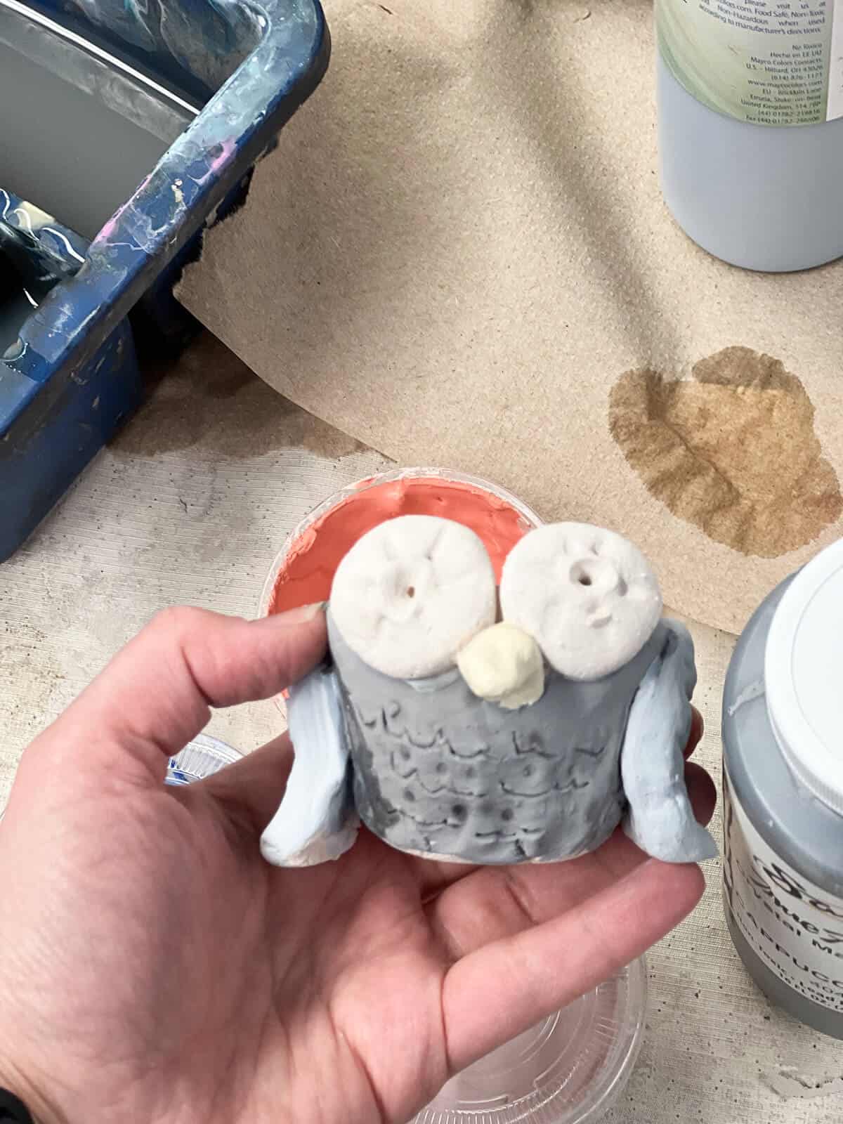 hand holding glazed clay art project for kids.