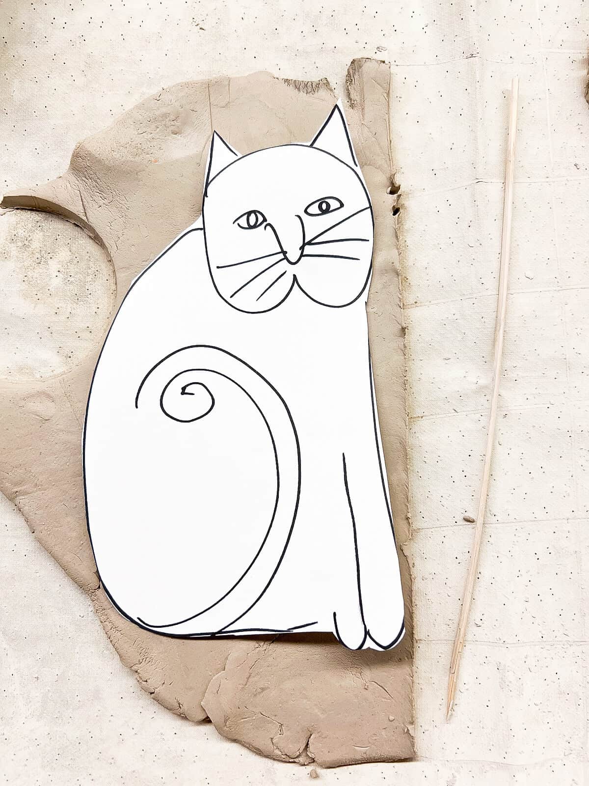 paper template with cat drawn on it on clay slab.