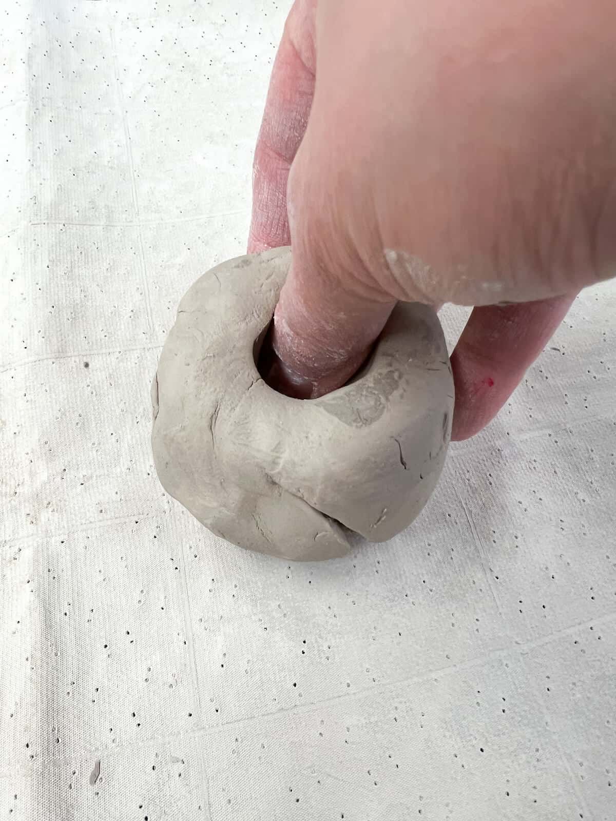 hand pinching clay to create a pinch pot.