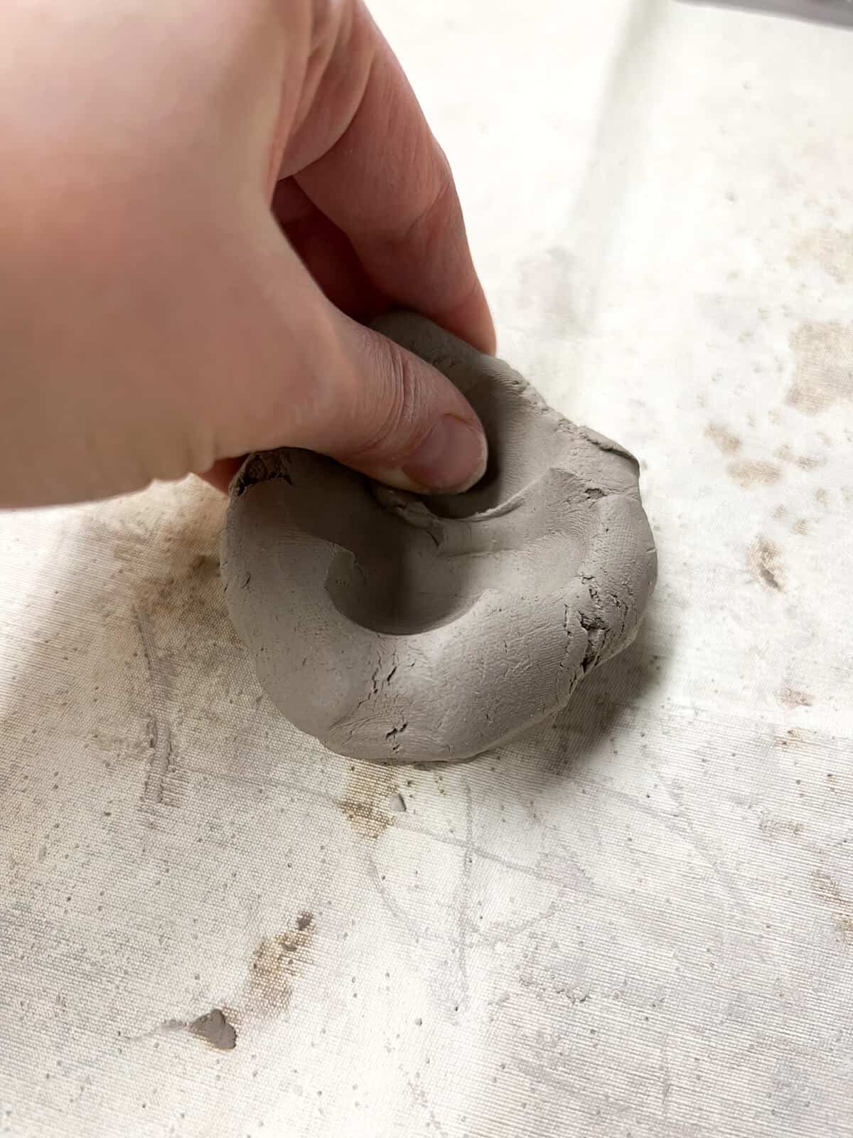 hand pinching edges of clay pot. 