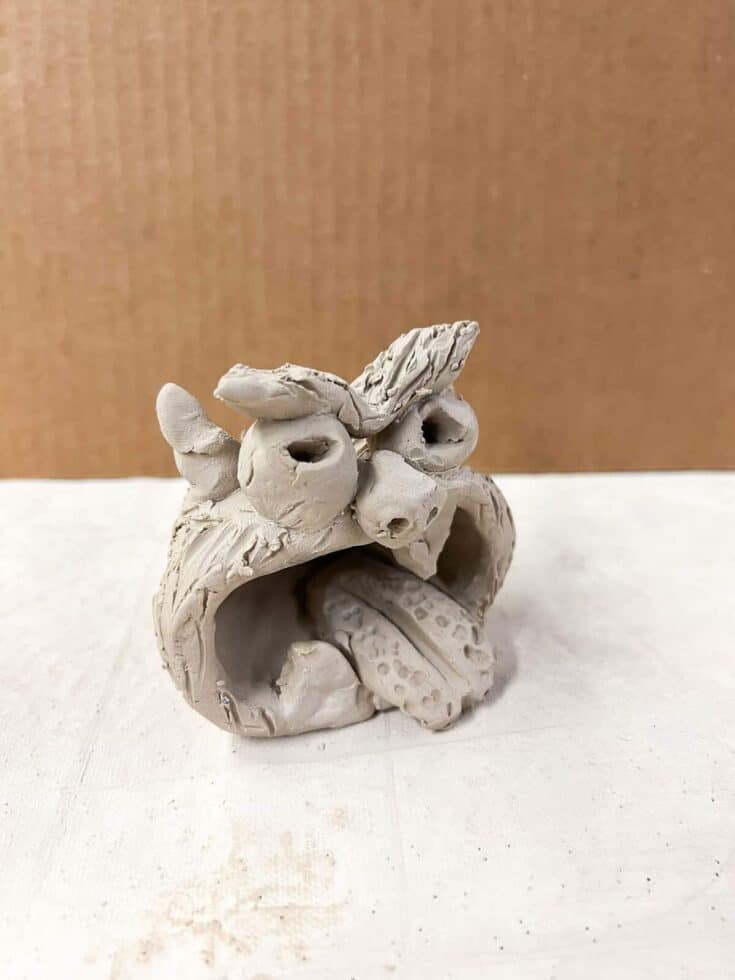 final pinch pot clay monster with eyebrows, horns, togue and big eyes before going in kiln.
