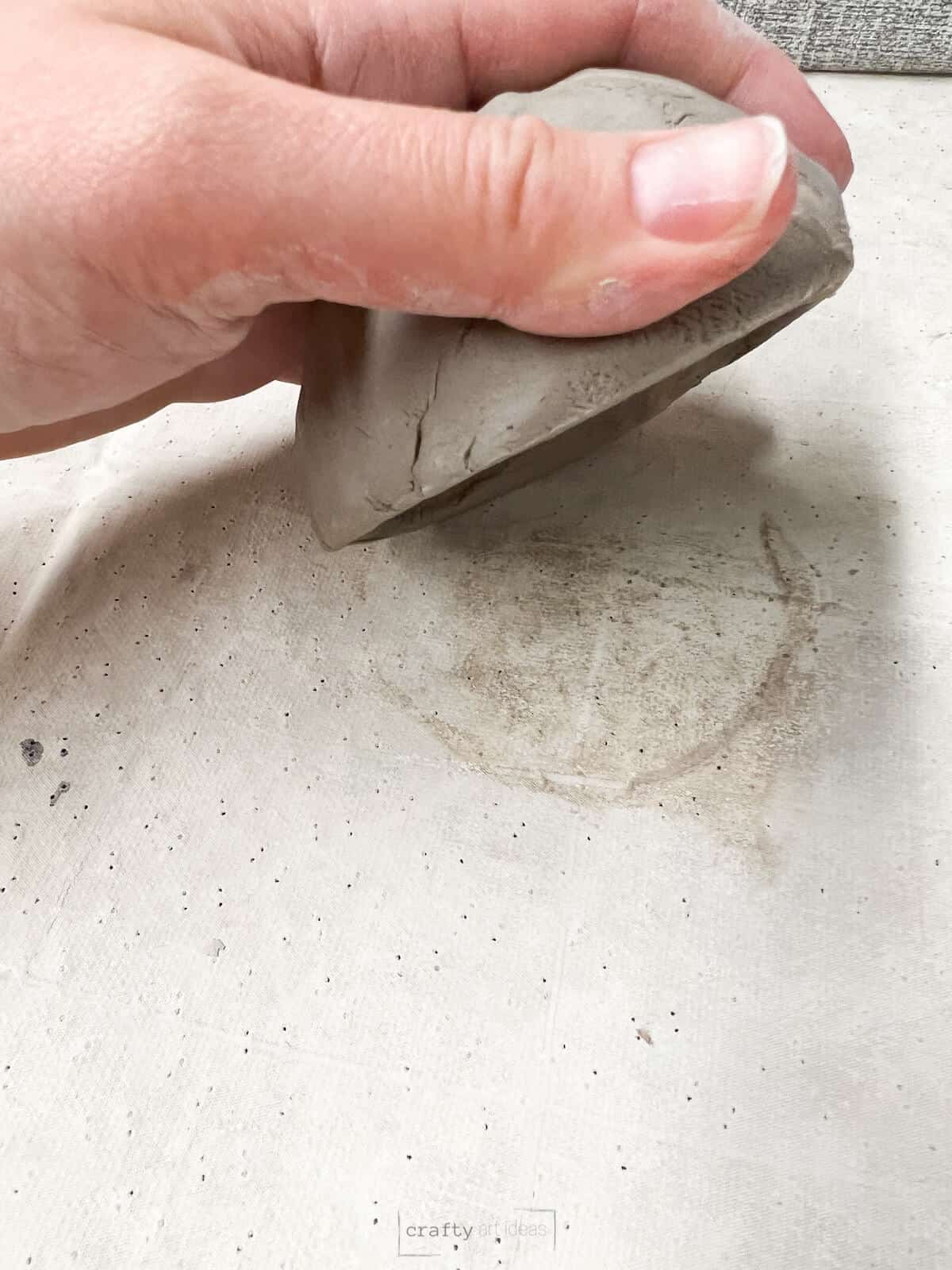 hand flipping over clay pinch pot.