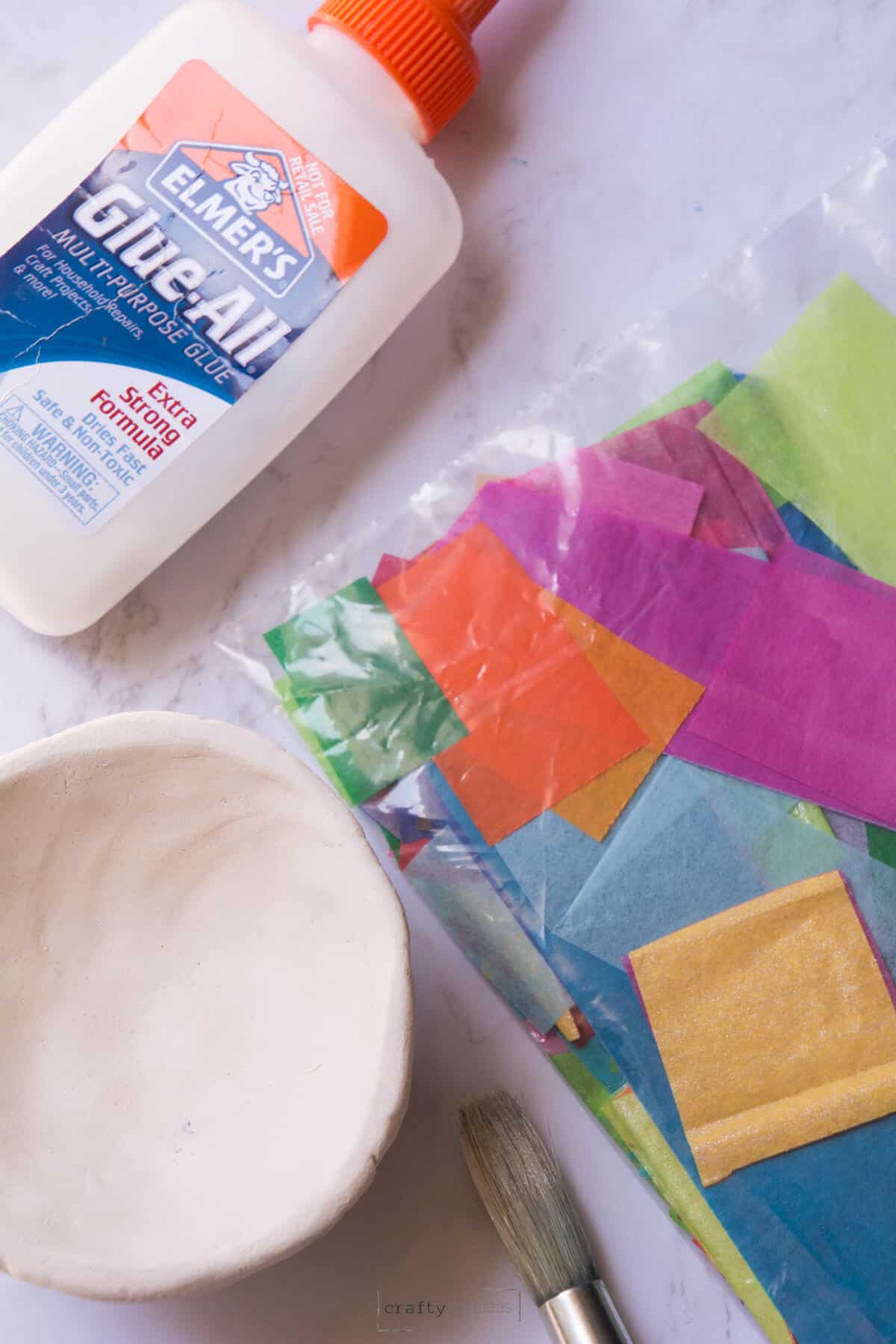 Elmer's glue with baggie of tissue paper squares and clay pinch pot.