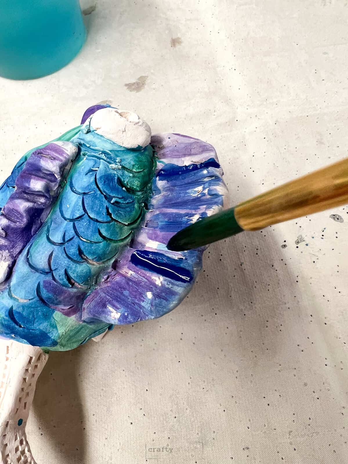 brush painting ceramic fish with watercolor paints.
