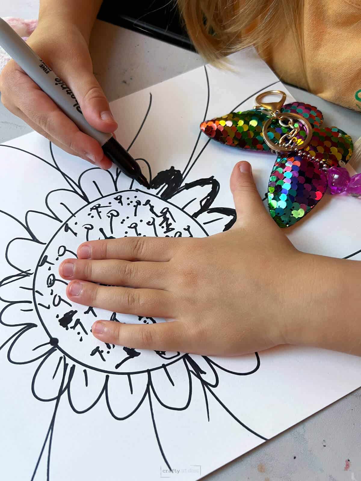 child making thicker black lines on part of her flower drawing.