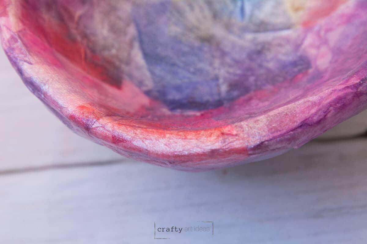 edge of clay bowl with decoupaged tissue paper and shimmer layer.