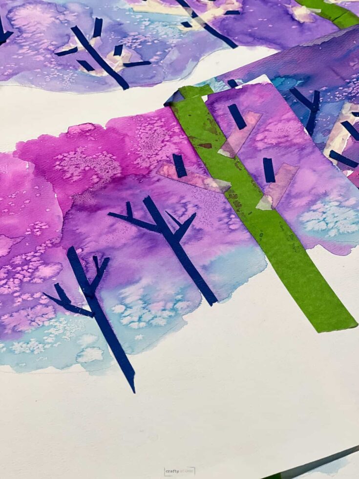 painter's tape on watercolor paintings of winter landscapes with magenta and blue skies.