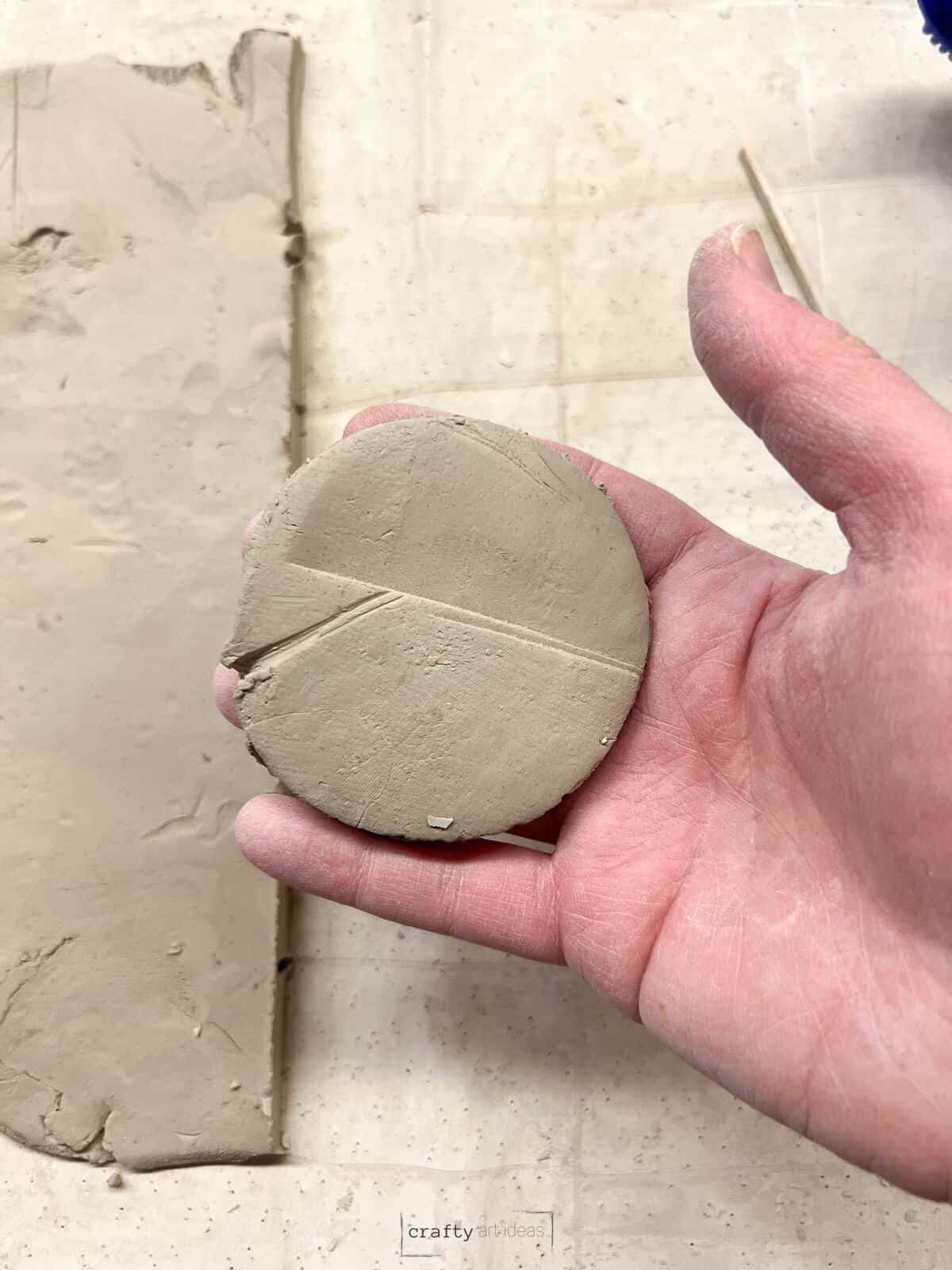 hand holding small clay circle slab.