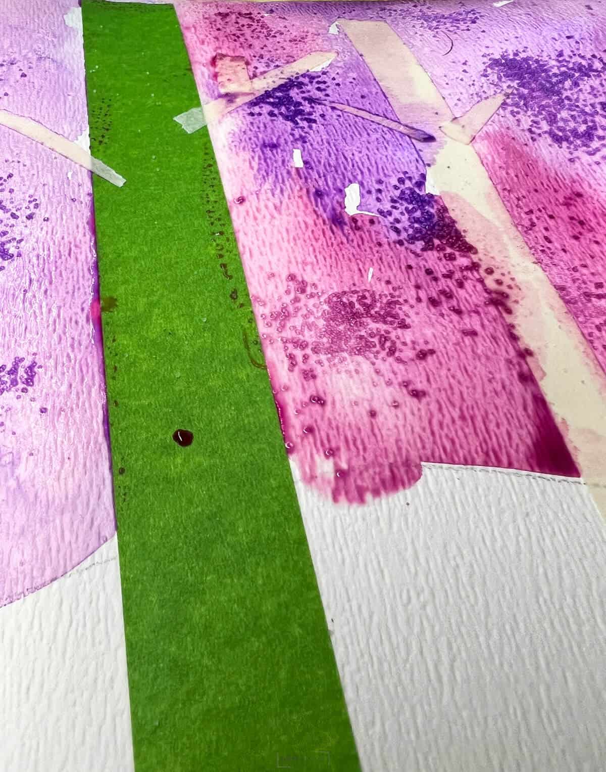 slat sprinkled in watercolor paint with taped trees on art lesson.