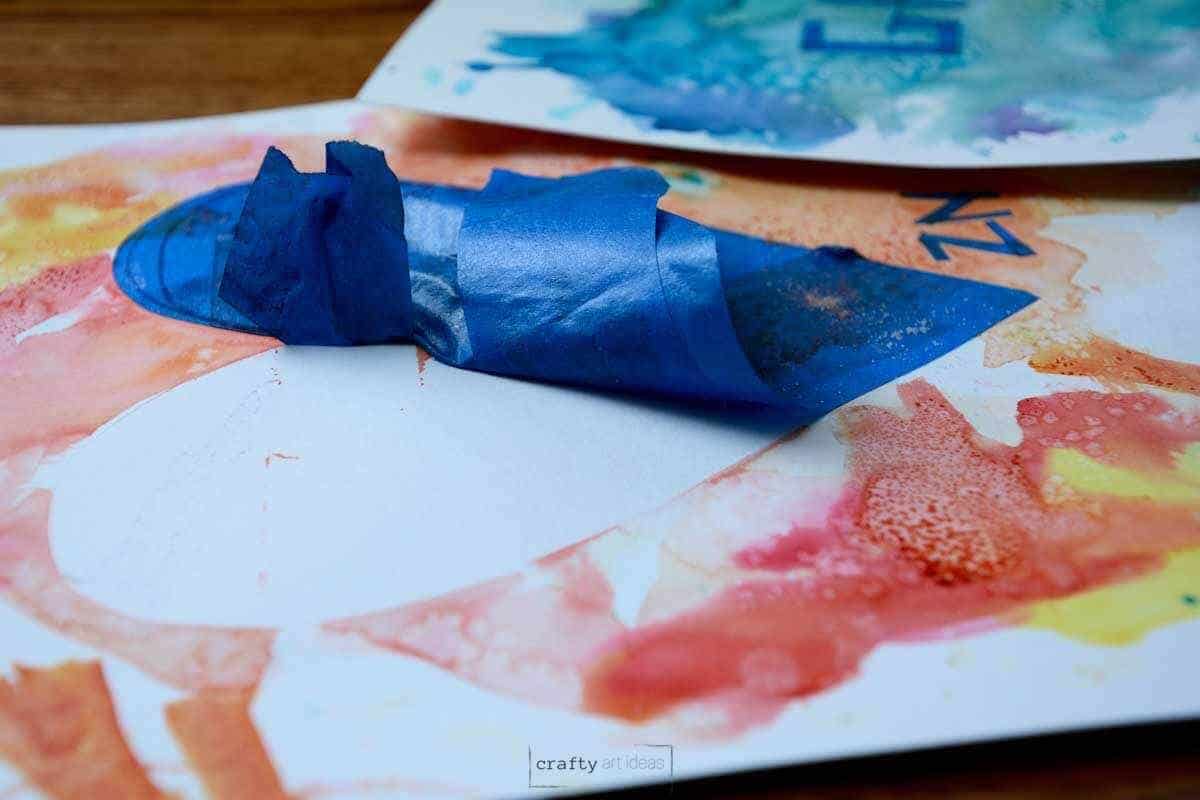 blue painter's tape partially peeled up from heart watercolor painting.