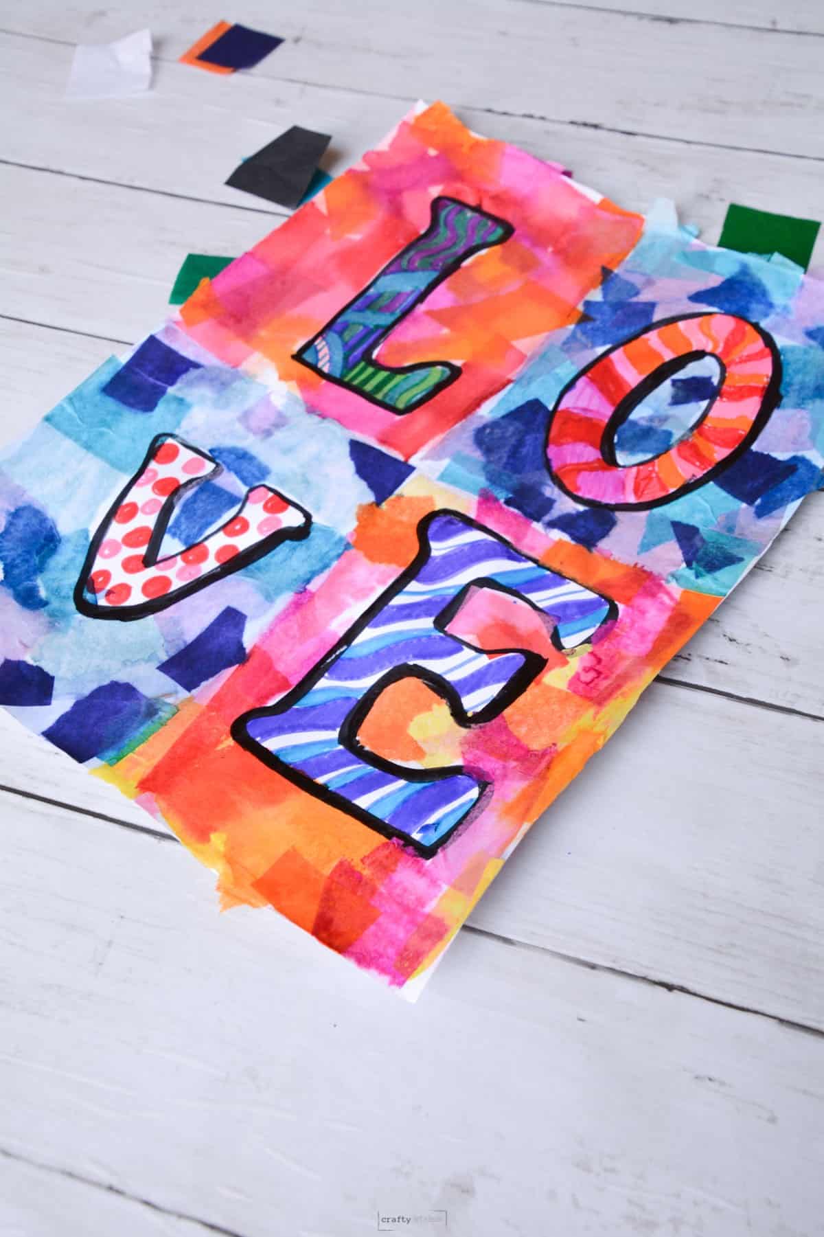 love spelled on art project with marker and tissue paper.