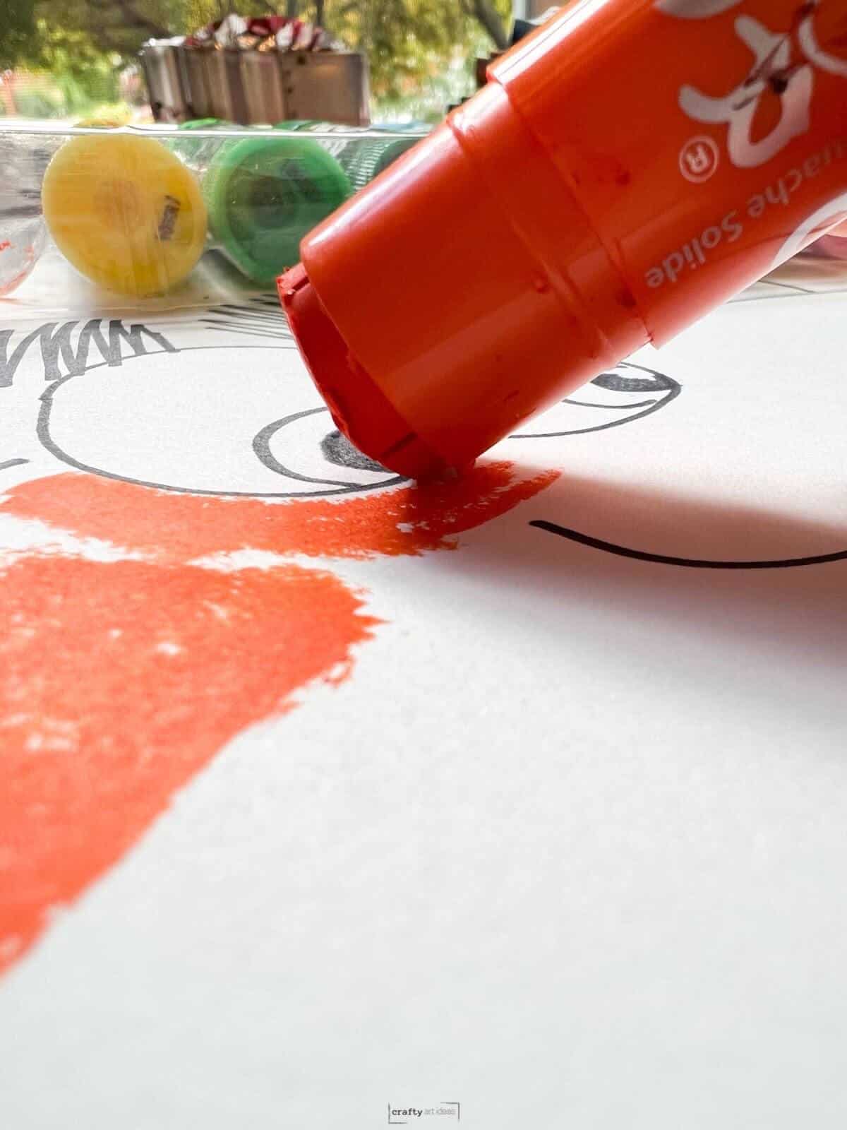 orange paint stick adding color to white paper.