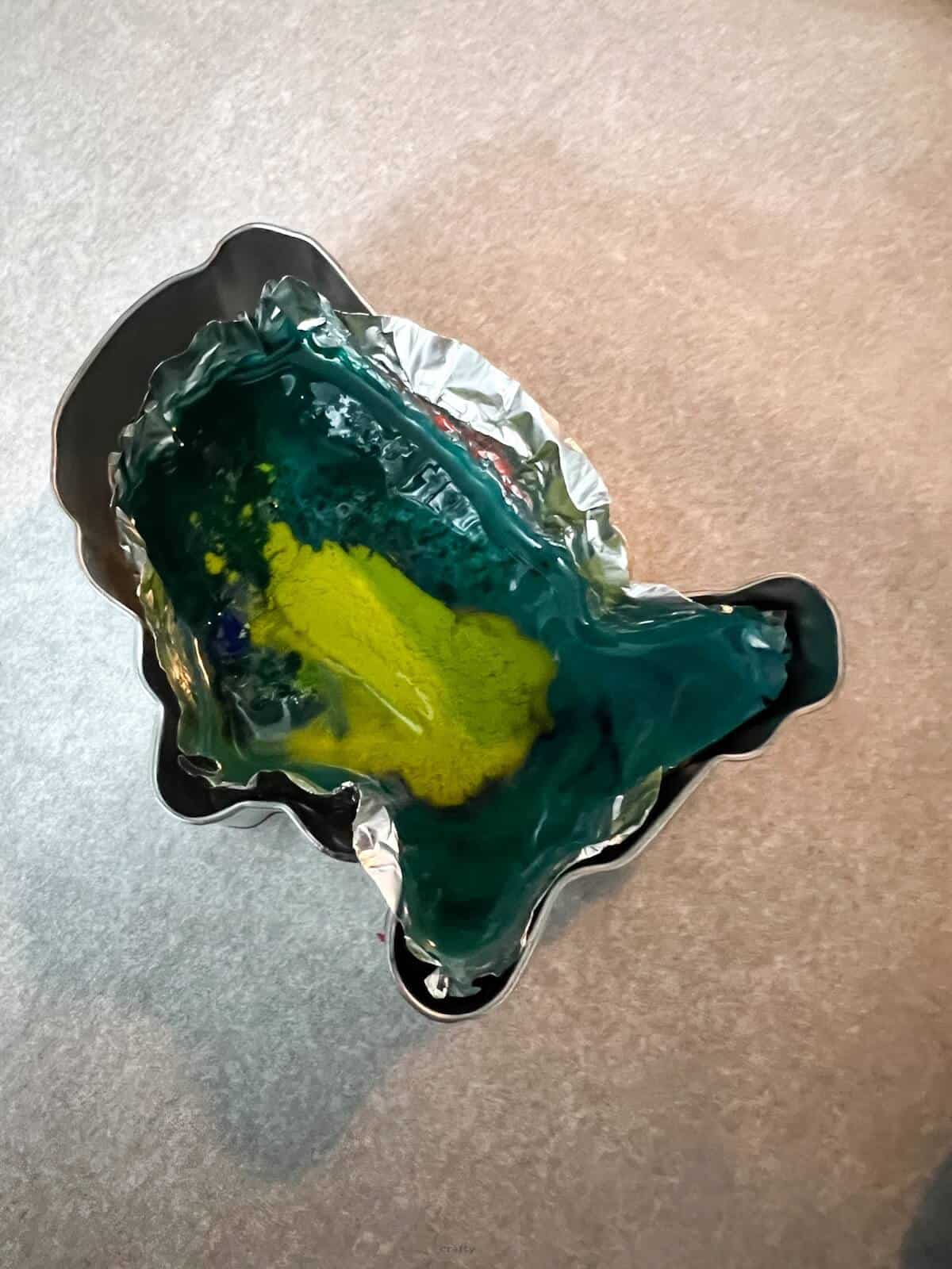 green, light green and blue melted wax inside of cupcake liner in USA cookie cutter.