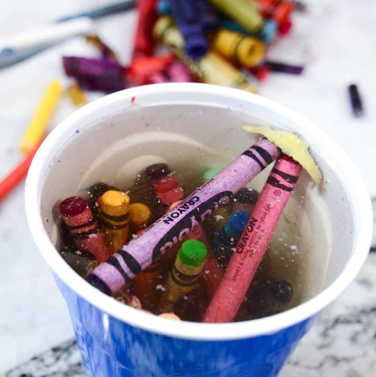 crayons soaking in water in cup.