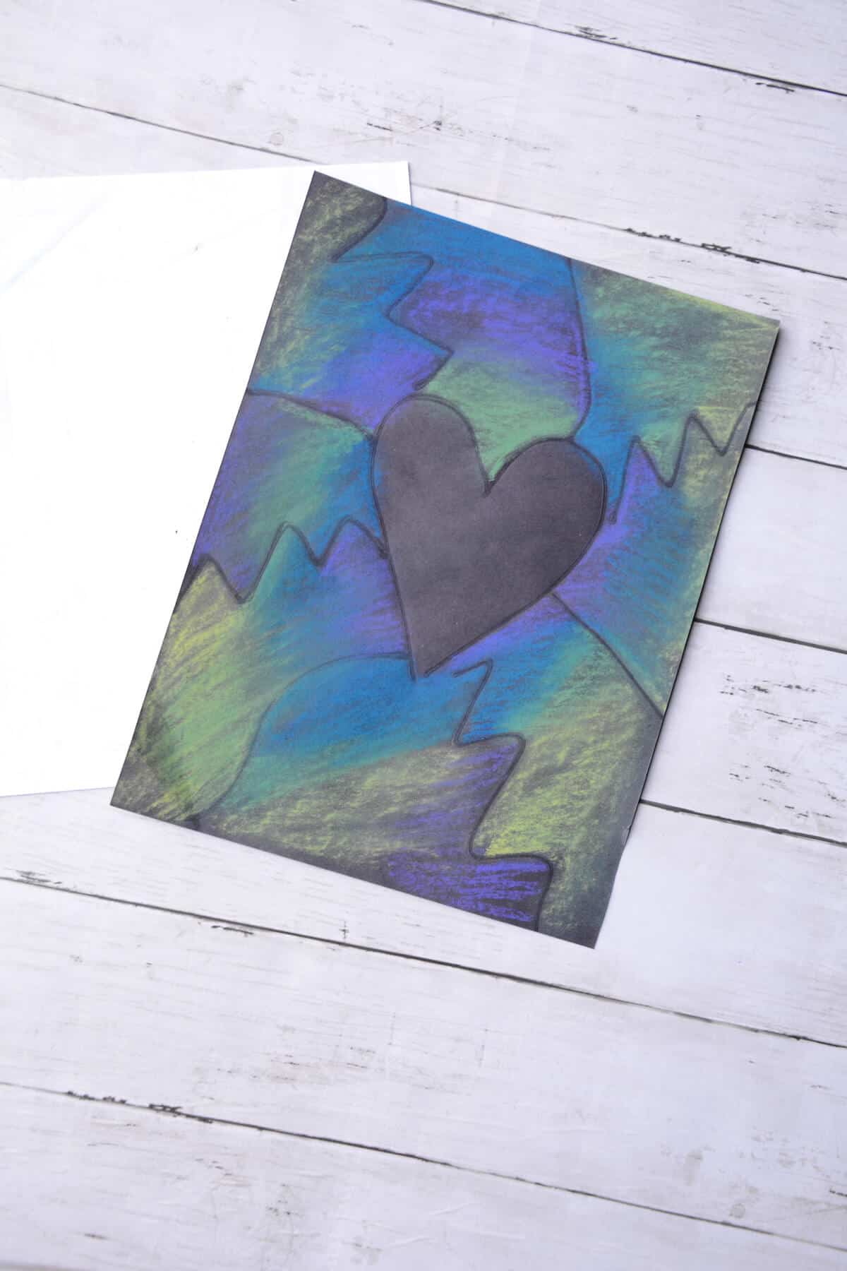 blue, green, purple chalk pastels on black paper around heart.