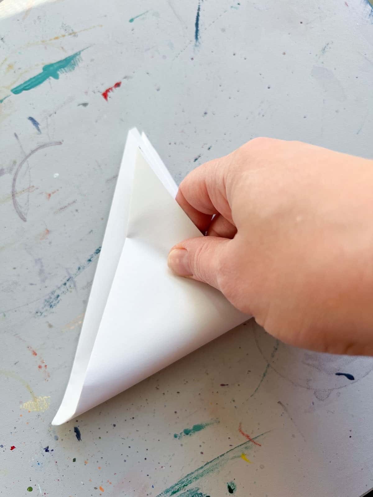 hand folding paper triangle for paper snowflake.