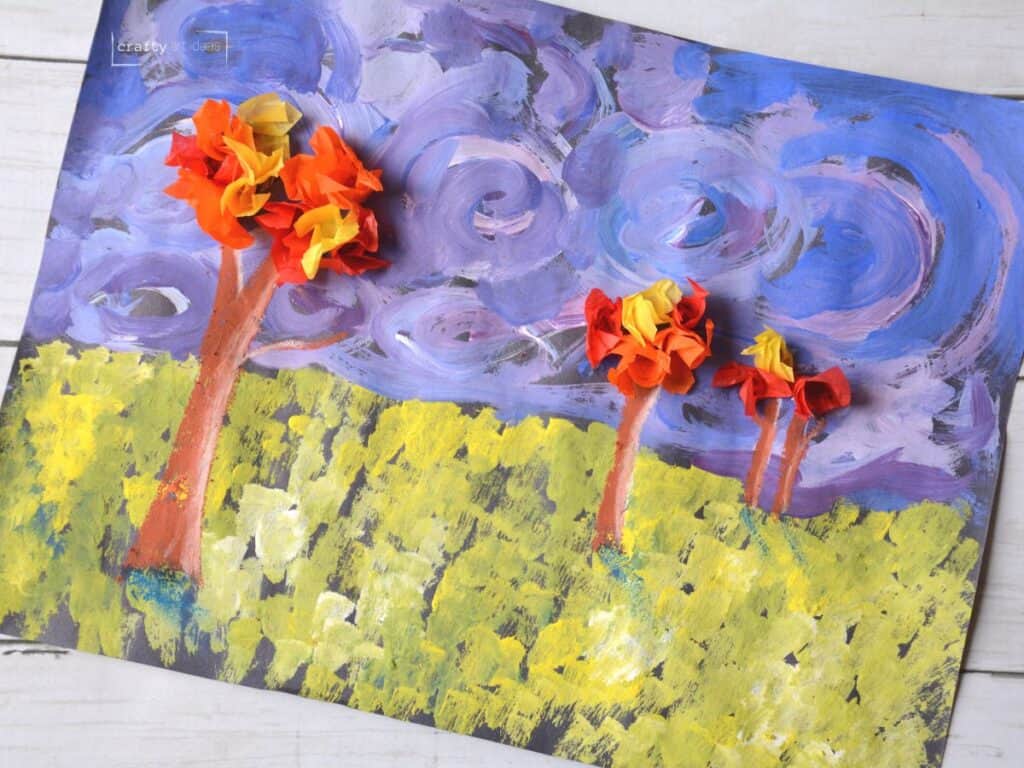 landscape painting with grass, swirly sky and 3 trees with tissue paper leaves.
