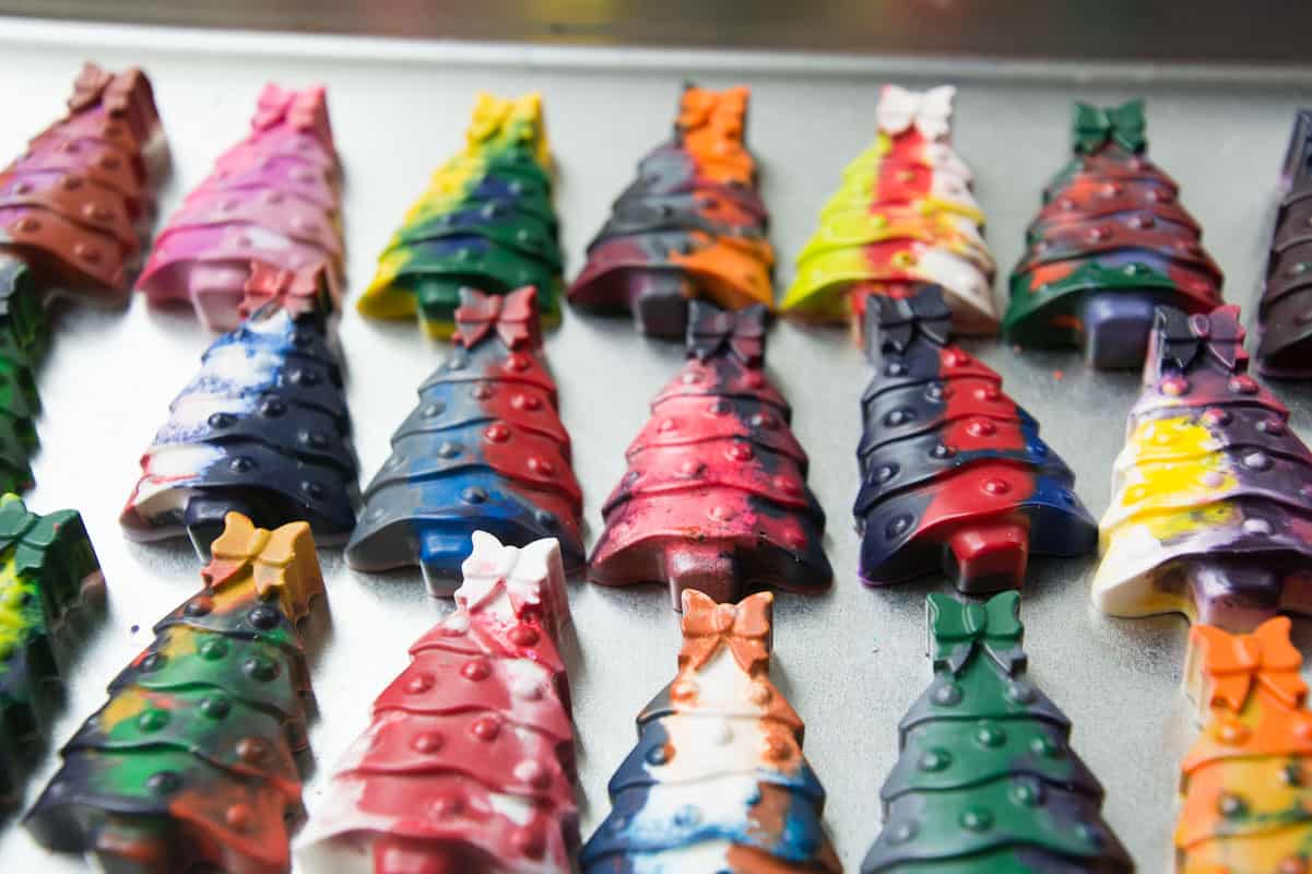 17 colorful DIY Christmas tree crayons on silver cookie sheet.