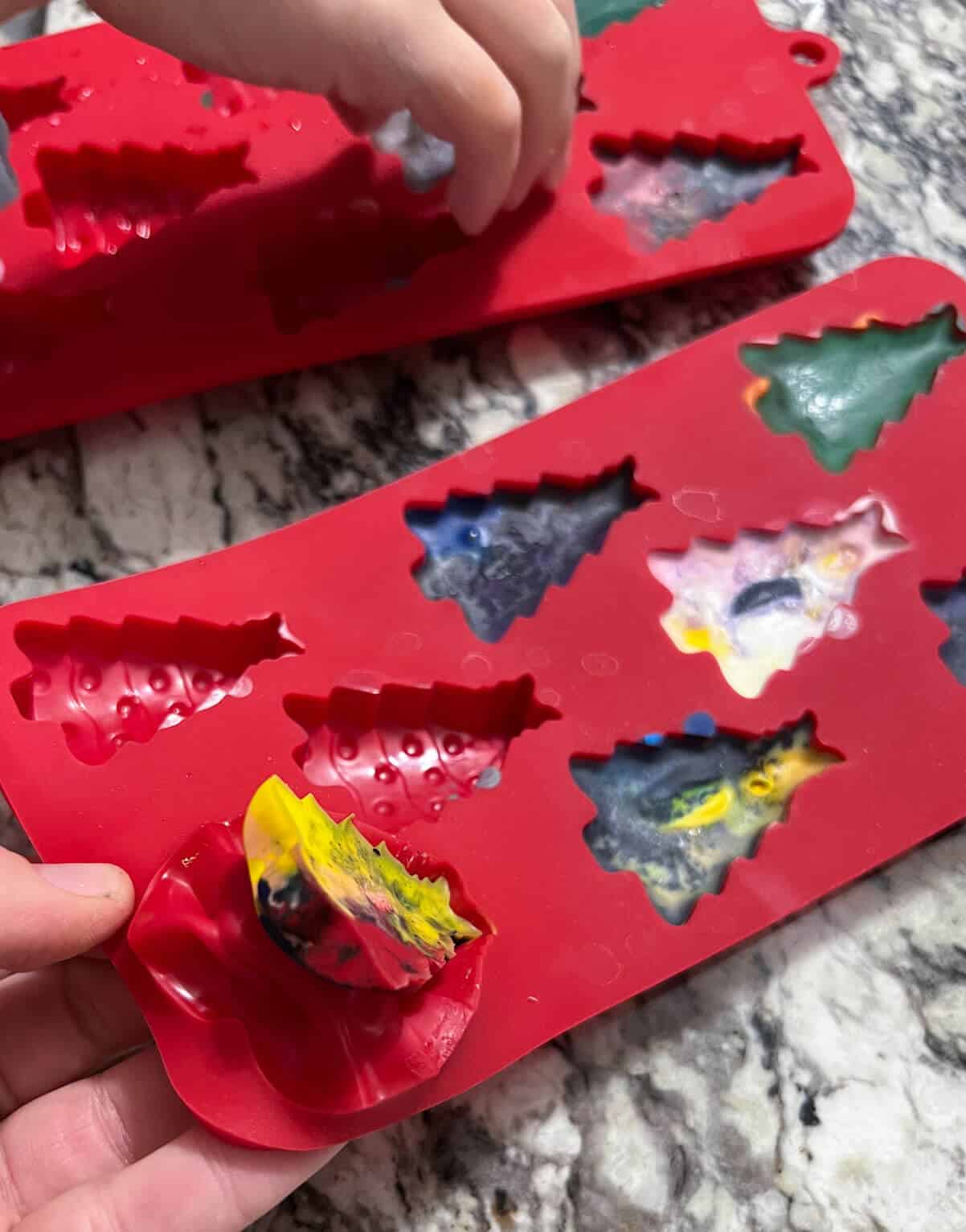 crayons in molds with hand starting to take them out.