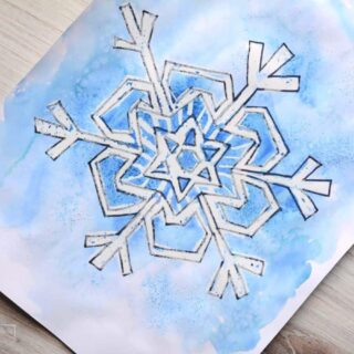 snowflake drawing with blue watercolor paint on wood table.