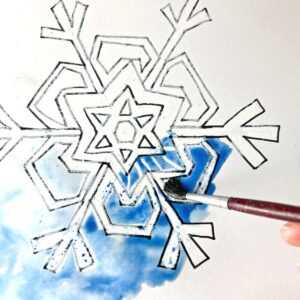 brush painting oil pastel resist snowflake with blue watercolor paint.