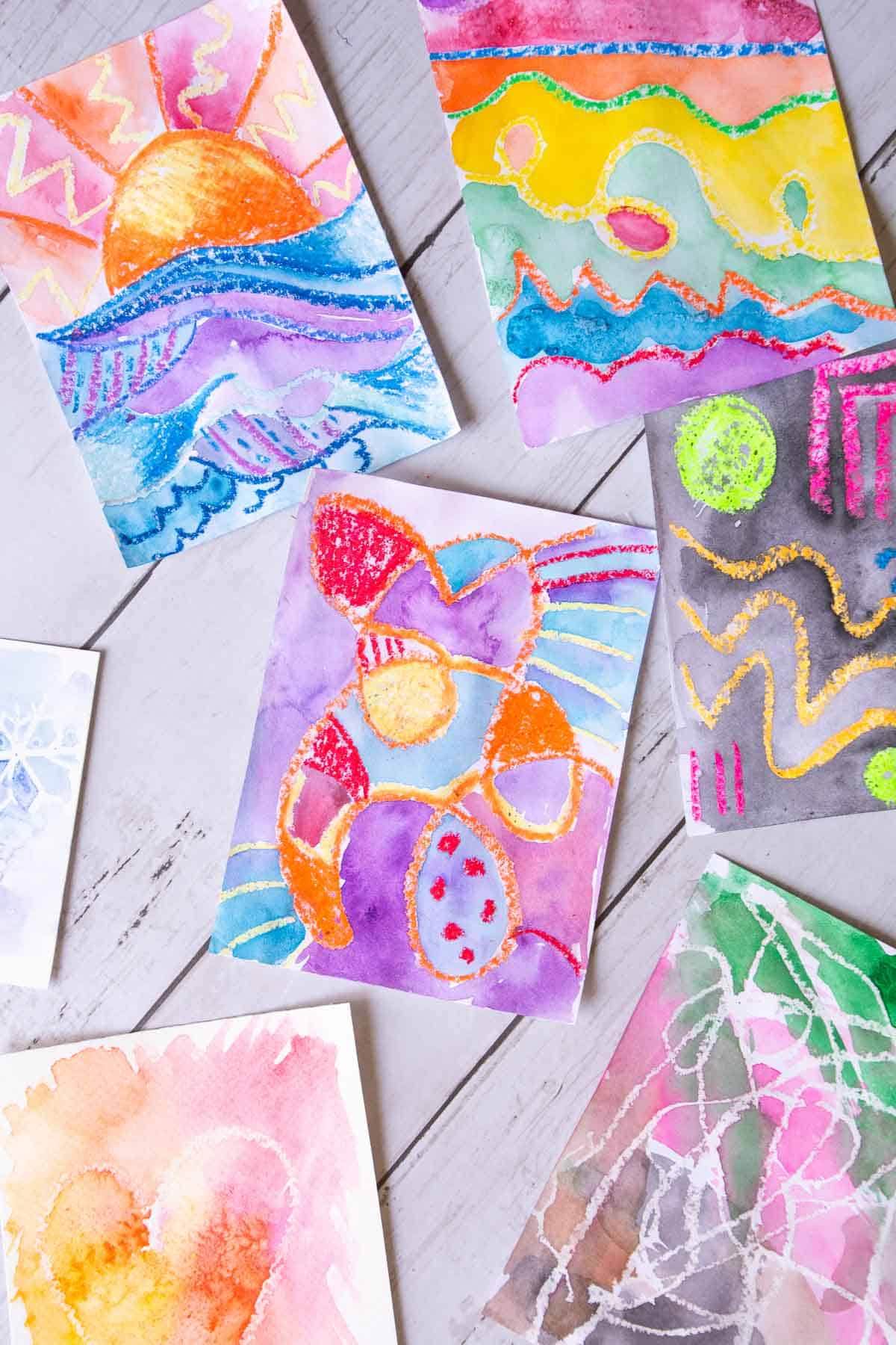 oil pastel and watercolor resist paintings on a table.