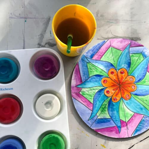 painted circle mandala project with water cup and paint palette on table.