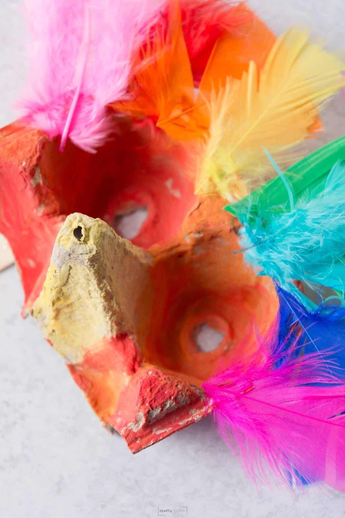 A colorful bird mask made from an egg carton.