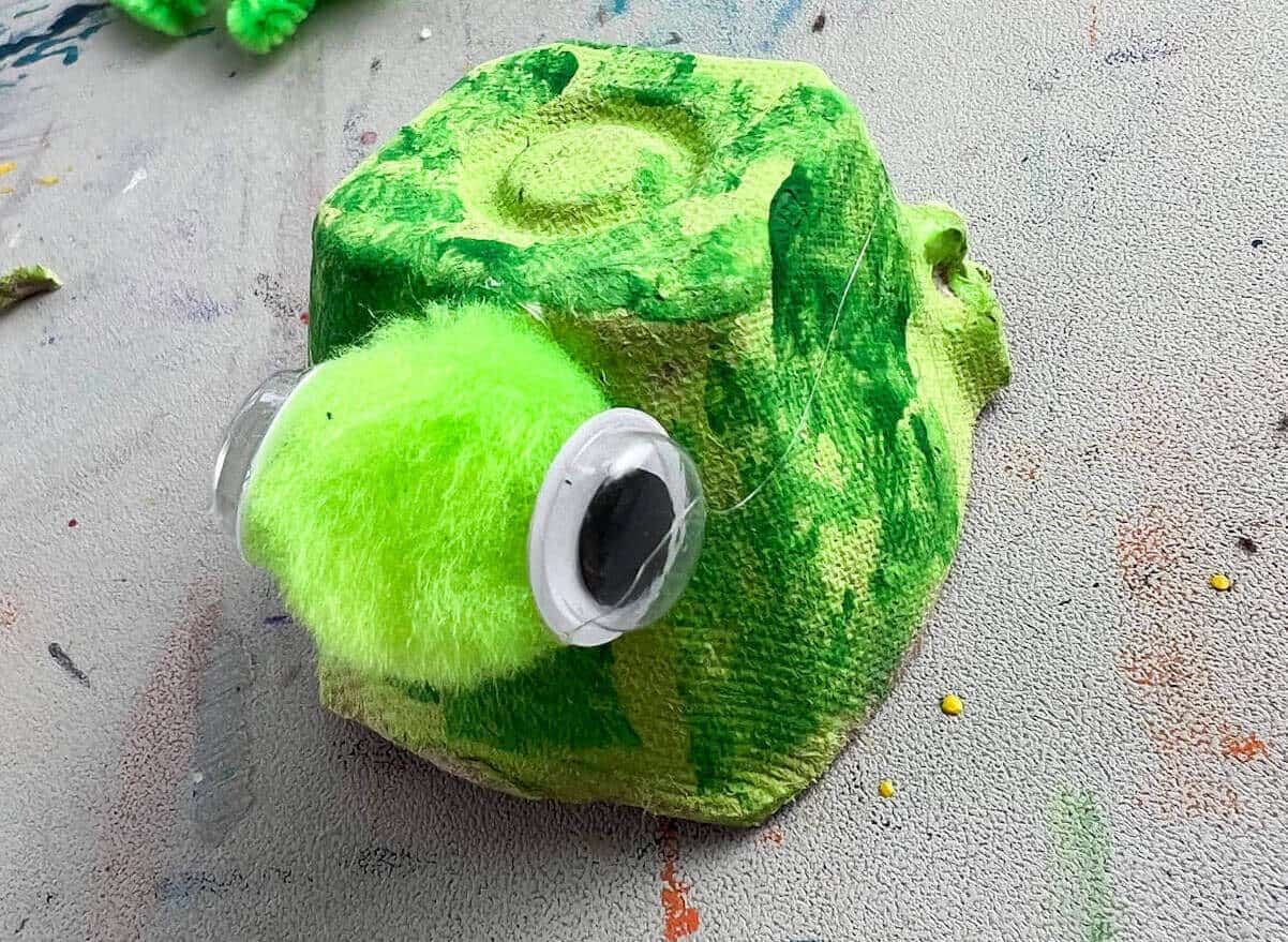 googly eyes on green pom pom for egg carton turtle craft.