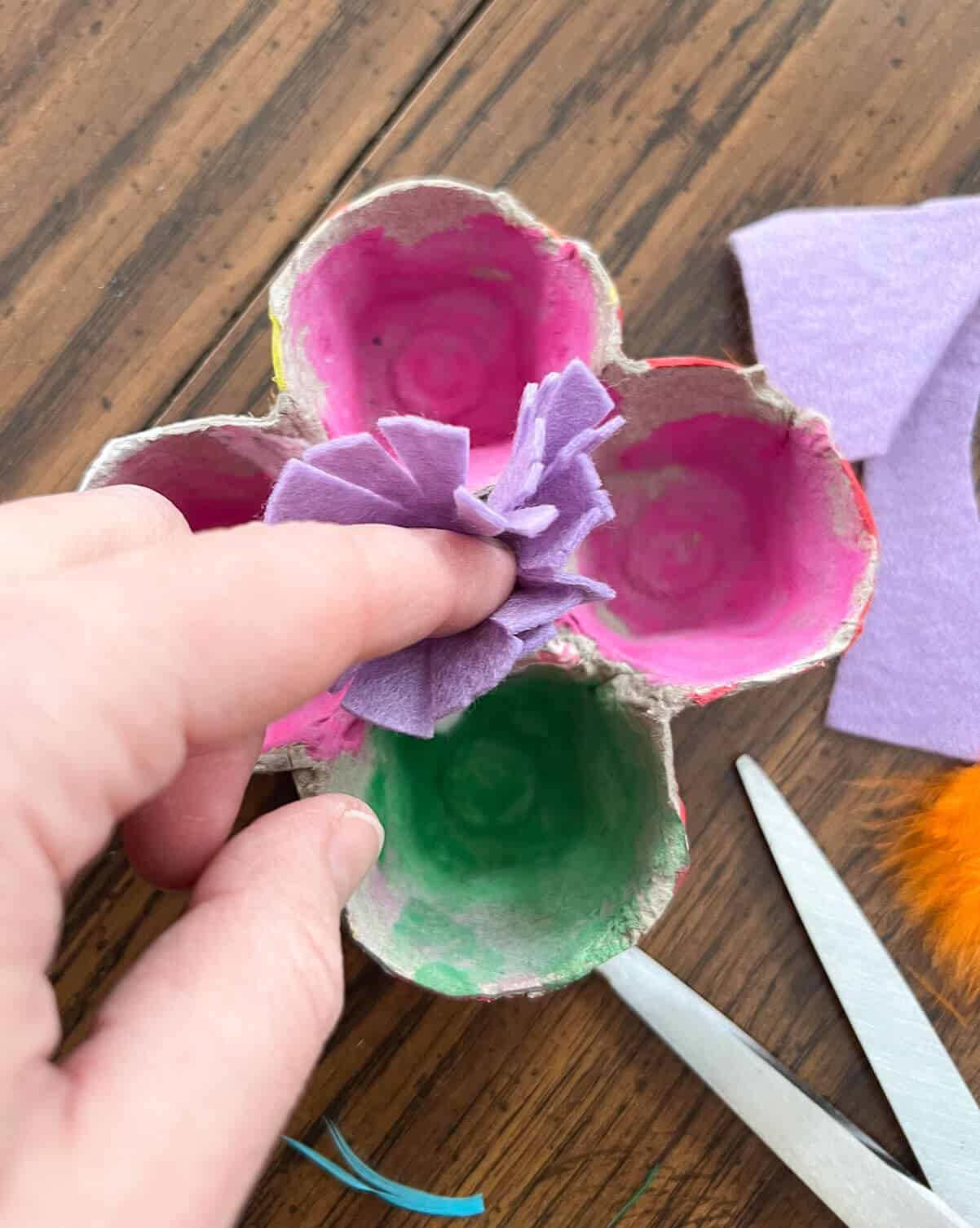 finger pushing felt inside painted flower craft.