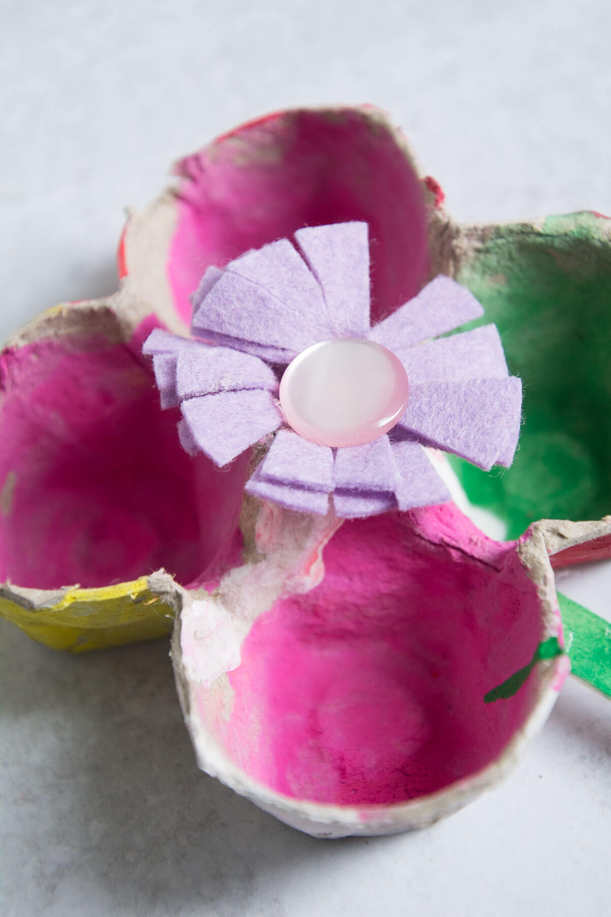 zoomed in view of egg carton flower craft with felt and button.