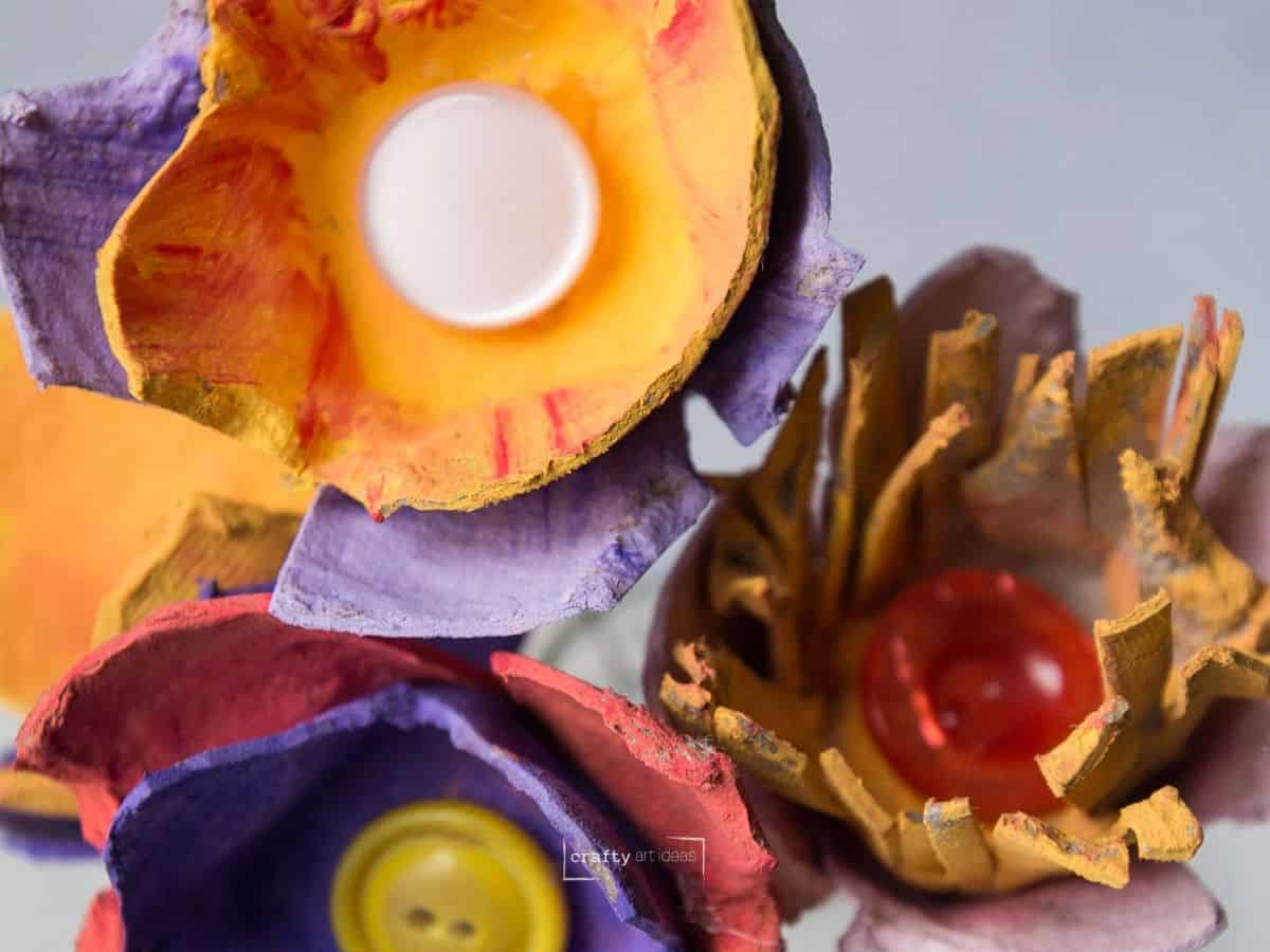 yellow, red and purple painted egg carton flowers with buttons in the center.