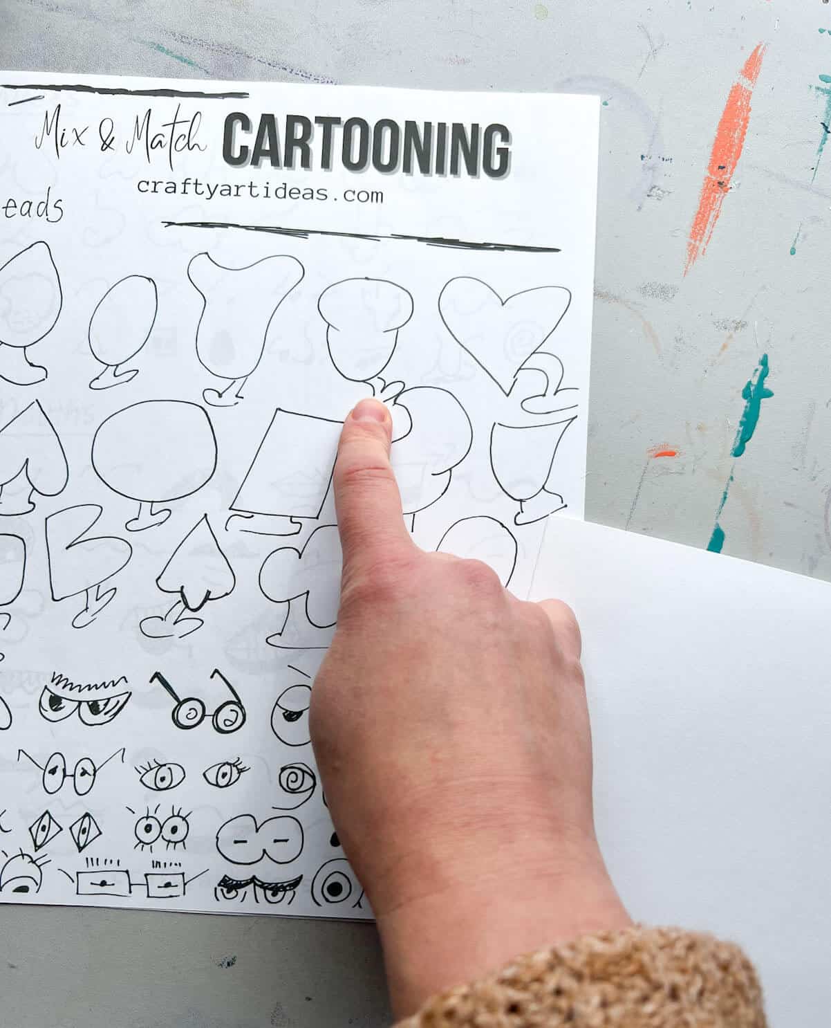 hand pointing to head shape in cartooning guide.