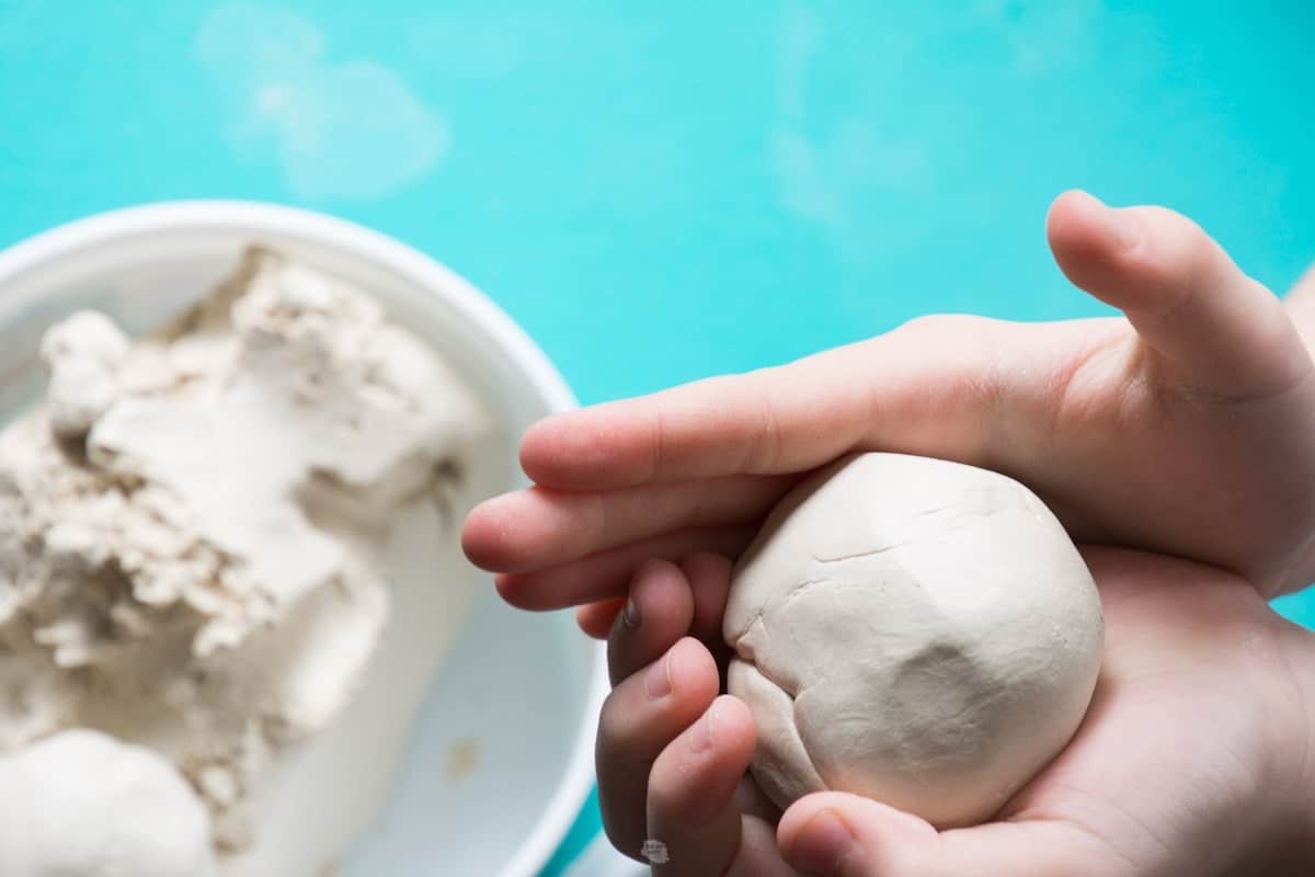 child rolling clay into a ball.