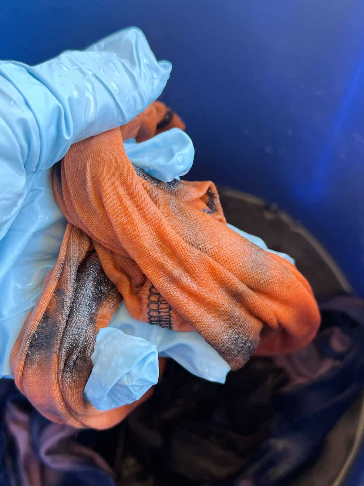 hand holding part of shirt being rinsed in water.