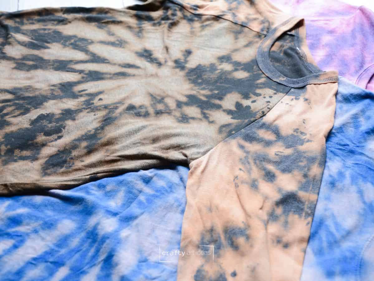 3 different reverse tie dye shirts on a table.