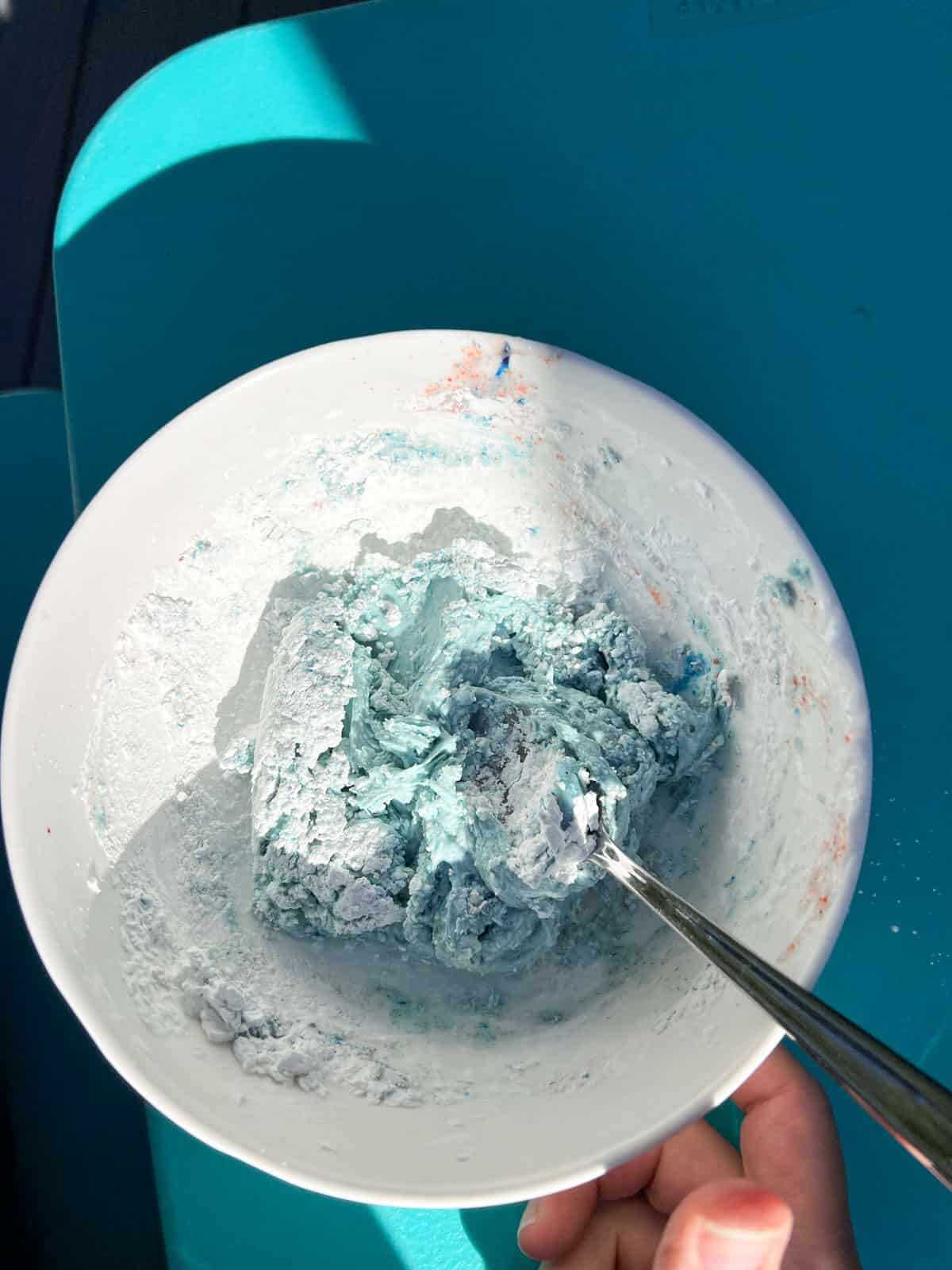 spoon in bowl with mixed blue cornstrach and conditioner.