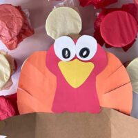 paper and cardboard turkey on cups covered in tissue paper.