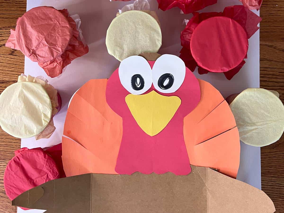 paper and cardboard turkey on cups covered in tissue paper.