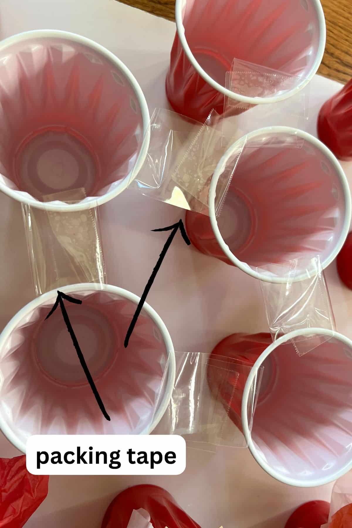 clear packing tape on the top of red plastic cups.