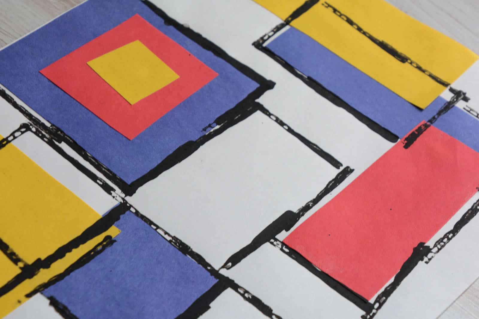collage of yellow, blue and red paper squares and rectangles with black lines.