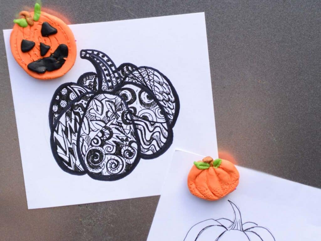 pumpkin drawings being held up with pumpkin clay magnets.