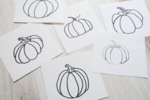 6 pumpkin drawings on a table.