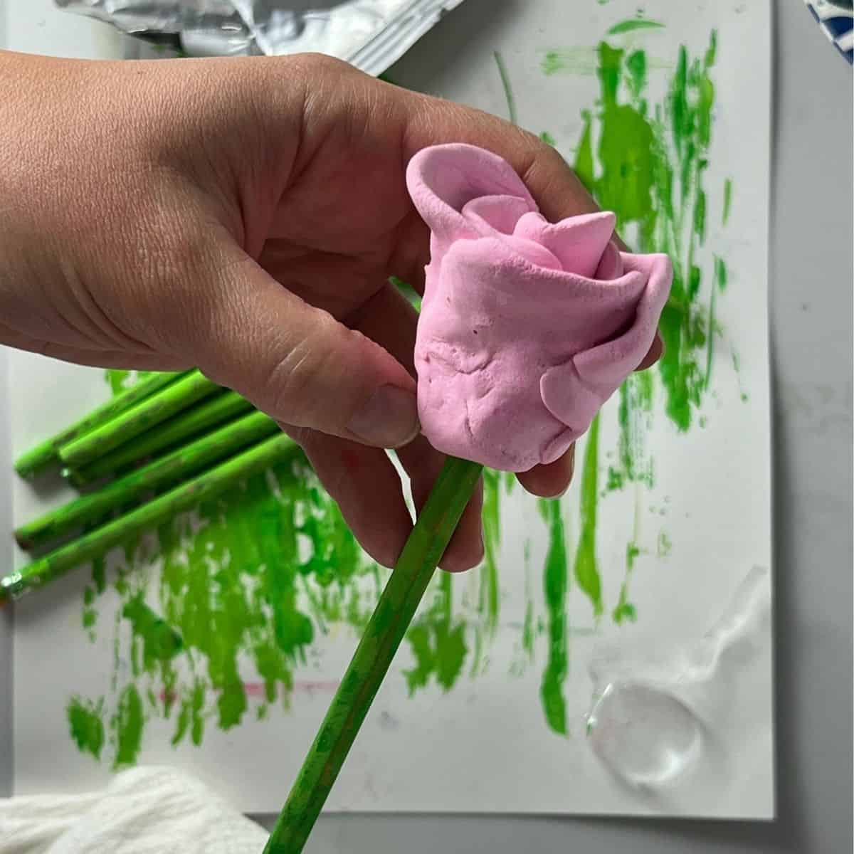 hand attaching green stem to flower craft.