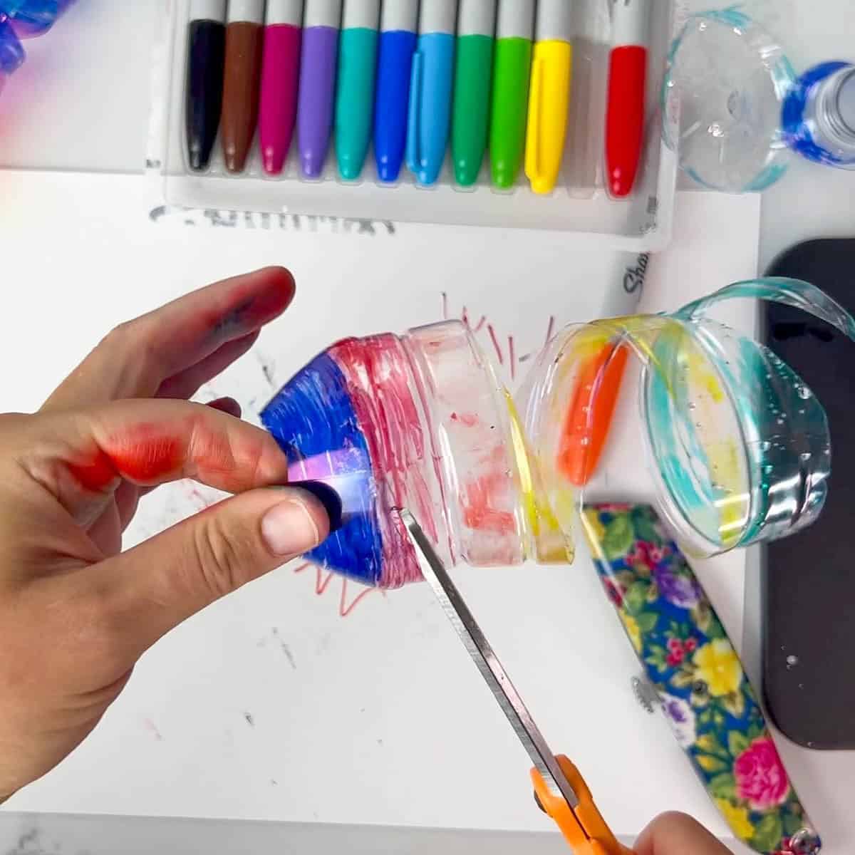 hands using scissors to cut plastic bottle.